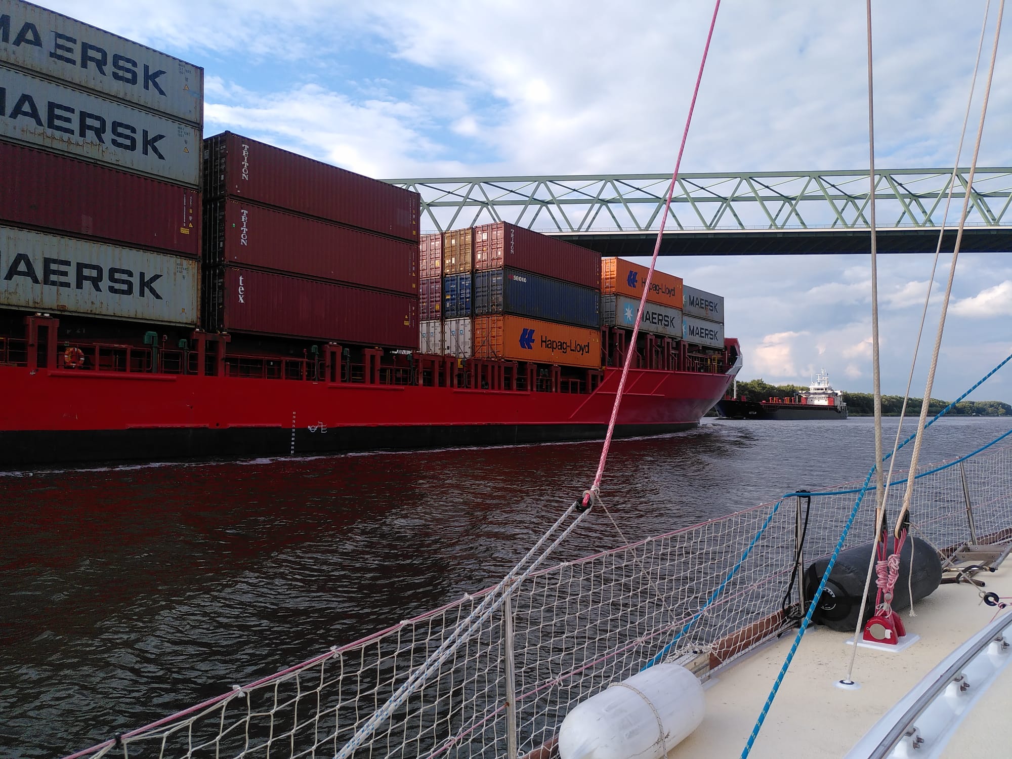 Container ship passing under canal bridge